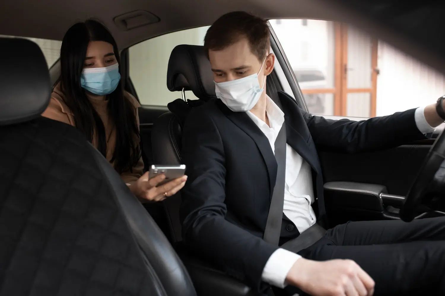 Course chris-taxi à blaye, chauffeur masqué aidant une passagère à l’arrière via son téléphone dans une voiture moderne